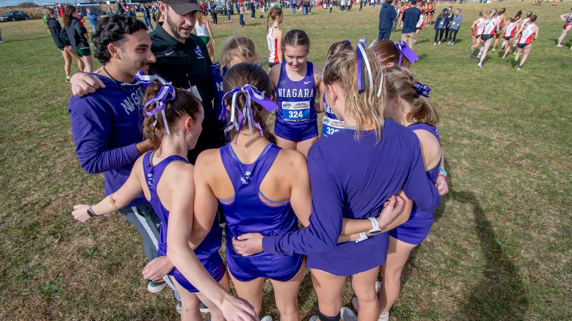 Niagara cross-country runners gathering in a team huddle at a meet